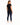 A woman stands with her back to the camera, wearing a black shirt and dark skinny jeans, paired with white sneakers.