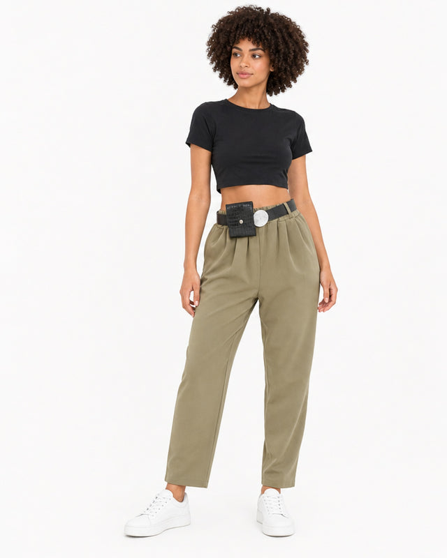 A model poses in olive green pants, paired with a black crop top and white sneakers.