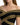 Close-up of a woman wearing an off-shoulder black top with intricate gold embroidery detailing.