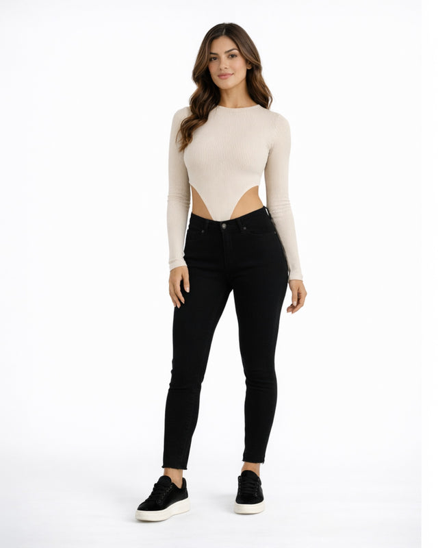 A model poses in a fitted ribbed top with cut-out sides, paired with black skinny jeans and sneakers.