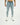 Men's light blue super jeans with distressed details and ripped knees on a model wearing white sneakers.