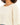 A close-up of a person wearing a light beige cropped top with a wide neckline and short sleeves.