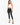 A model poses in a white crochet halter top and black skinny jeans, complemented by strappy black heels.