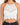 White crochet halter top featuring intricate patterns and a scalloped hem, styled with high-waisted black jeans.
