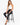 A woman sits on a black stool wearing a white crochet crop top and black high-waisted jeans with strappy heels.