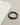 A black and gray beaded bracelet rests beside a folded light-colored shirt on a textured surface.