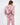 A woman with long hair wears a loose, pink hoodie with a gathered hem and oversized sleeves, styled casually.