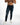 A man wearing dark blue distressed jeans and white sneakers, standing against a plain white background.