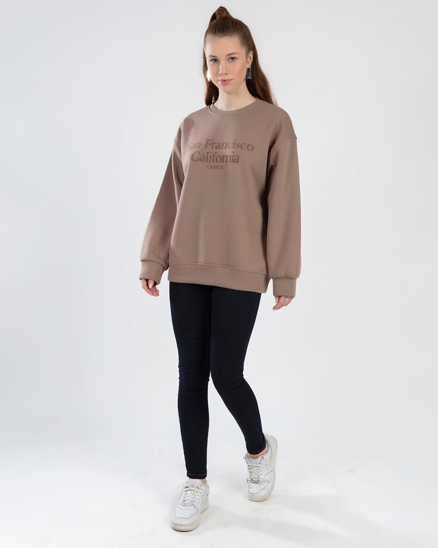 Brown oversized San Francisco California embroidered sweatshirt worn with black leggings and white sneakers.
