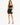 A model poses in a fitted black skirt and matching crop top, showcasing a sleek, stylish look.