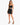 A model poses in a black crop top and matching fitted skirt, paired with strappy high-heeled sandals.