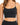 A close-up of a woman wearing a black, sleeveless, cropped top with thin straps and a subtle shimmer.