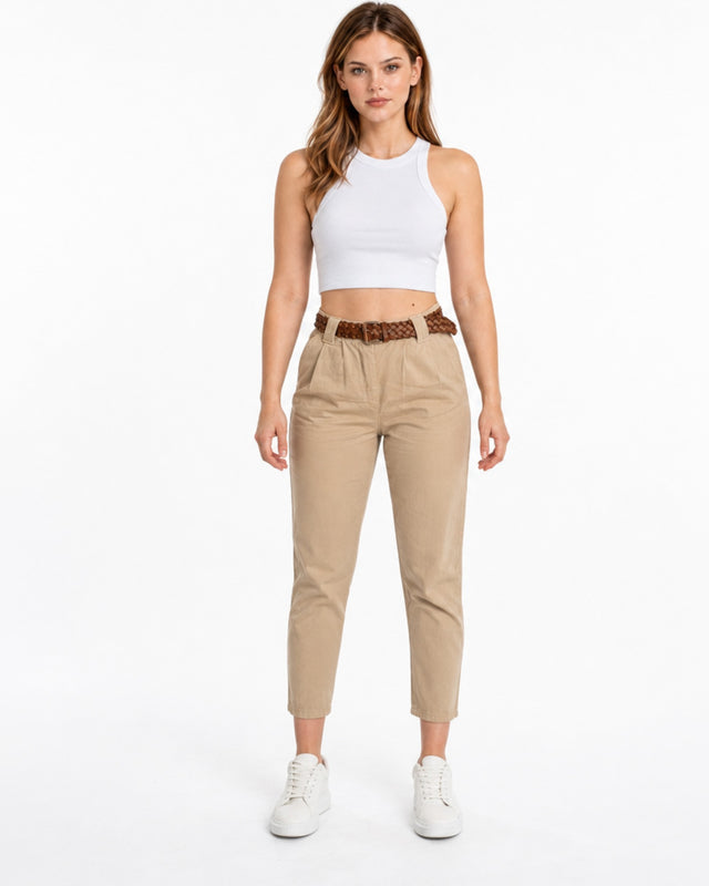 A model wearing beige cropped pants with a braided brown belt and white sneakers, posing against a plain background.