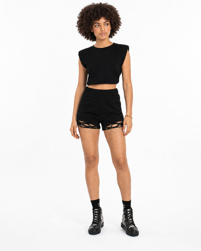 A model stands confidently in black shorts featuring unique cut-out details, paired with a matching cropped top and b...