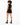 A model with curly hair wears a black sleeveless top and matching shorts, paired with stylish black boots.