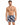 A man stands confidently in colorful swim trunks featuring a modern abstract pattern, showcasing a relaxed summer vibe.