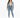 A woman stands confidently in light blue jeans paired with a cropped green top and a denim jacket.