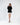 Model wearing a Celine black turtleneck knit sweater with a distressed fringe hem, paired with a white skirt.