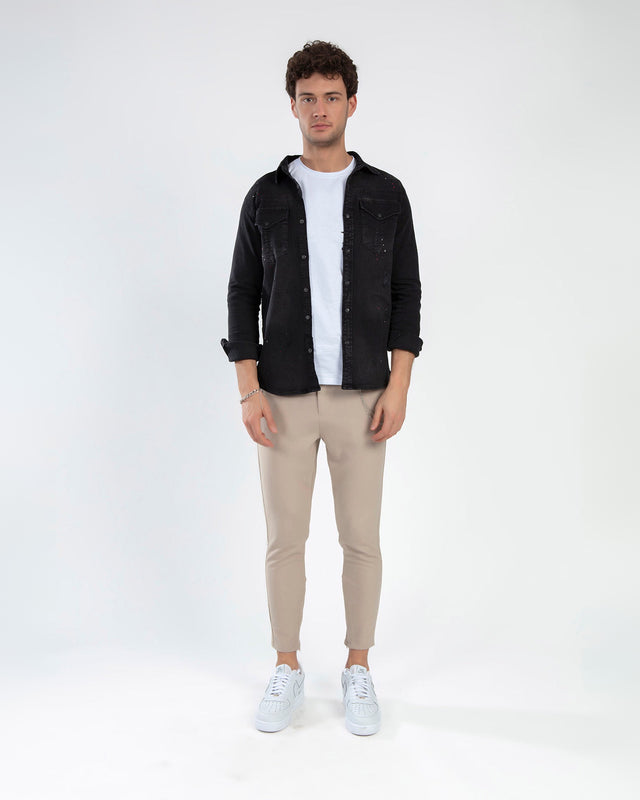 Man wearing Kaiden black washed denim shirt with chest pockets over a white tee and beige trousers.