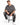 A man sits on a black stool wearing a gray oversized t-shirt, distressed jeans, and white sneakers.