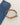 A tan belt with a gold buckle positioned next to folded blue denim jeans on a light fabric background.