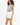 Model in L.A. streetwear tank top in blue grey with raw hem and California graphic, paired with white denim shorts.