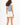 Back view of woman in Blue Grey L.A. Essential Tank Top with raw hem and white high-waisted streetwear shorts.