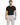 A man wearing a fitted black t-shirt paired with light gray trousers featuring a chain detail.