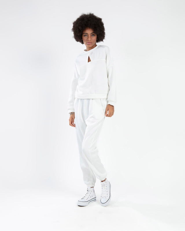 Model in a Carbon white matching two-piece lounge set featuring a cutout collar sweatshirt and jogger pants.