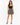 A woman stands confidently in a black crop top and a patterned mini skirt, paired with stylish high heels.