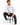 A man sits on a black stool wearing a long-sleeve white shirt with graphic text, paired with dark jeans and white sne...