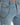 Light blue jeans featuring a distressed design and a silver chain accessory attached to the waistband.