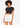A young woman with curly hair wears a fitted black top and white high-waisted shorts, posing confidently.