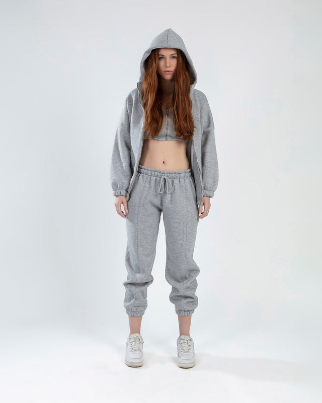 Model wearing Lily light grey matching jacket set with hooded zip-up, crop top, and drawstring joggers.