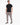 A man stands confidently in a fitted black short-sleeve shirt paired with light gray cargo pants and stylish sneakers.