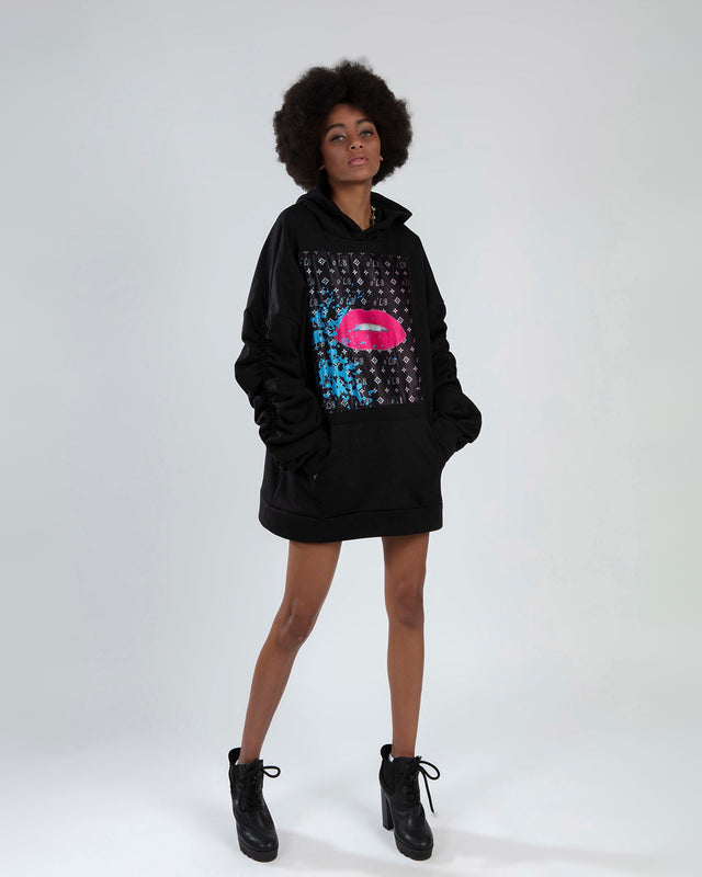 Model in an oversized black hoodie with a pink lips graphic print, ruched sleeves, and front pocket.
