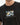 A close-up of a black t-shirt featuring a colorful geometric pattern and a handwritten-style text design.