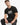 A man wearing a black t-shirt with a colorful geometric design sits casually, showcasing a relaxed style.