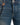Close-up of blue denim jeans featuring orange drawstring detail and contrasting stitching.