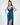 A model poses in a sleek, deep blue satin dress with a plunging neckline and a thigh-high slit.
