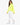 A woman stands in a bright yellow, oversized top paired with white joggers and white sneakers.