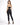 A woman stands with her back to the camera, wearing a black cropped top and fitted black jeans, paired with high-heel...