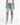 A person wearing distressed light blue jeans with large knee rips, paired with white sneakers and a fitted top.
