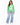 A woman stands wearing a green sweatshirt with bold white lettering, paired with light blue wide-leg jeans and white...