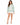 A woman stands wearing a mint green sweatshirt with bold text design, paired with a white skirt and heels.