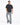 A man stands confidently black t-shirt and distressed light-wash jeans with paint splatters.