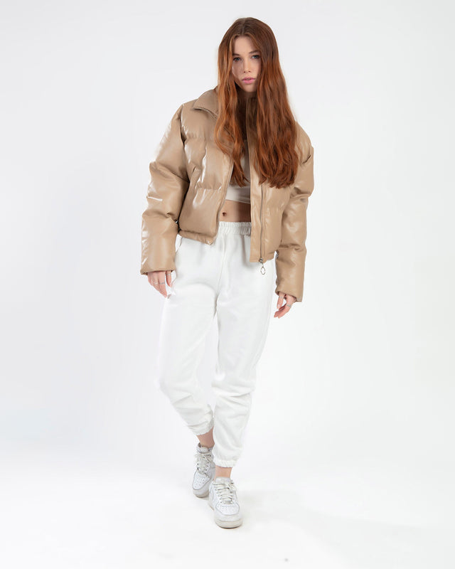 Model wearing Thea beige puffer coat with white joggers and sneakers, street style fashion.