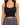 Black ribbed crop top with wide straps, paired with a patterned pleated skirt.
