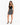 A woman stands confidently in a fitted black top and a flared black and white patterned skirt, paired with strappy he...