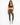 A woman stands confidently in fitted brown leggings and a dark sports bra, paired with stylish sneakers.